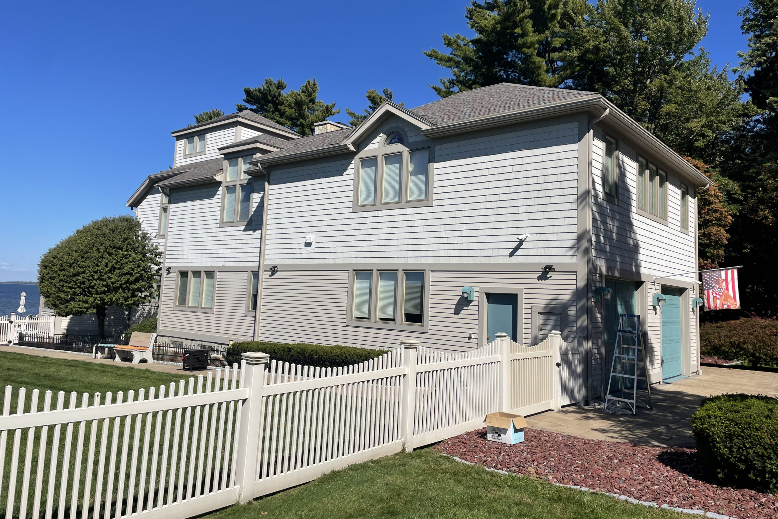 A large, olive-green Victorian house with a turret and white trim under a cloudy sky.
