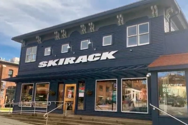 A navy blue two-story storefront with a large white "SKIRACK" sign.